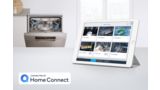 Auf dem Bildschirm eines auf der Arbeitsfläche abgestellten Tablets werden die Home Connect App und die Status aller verbundenen Geräte angezeigt