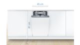 Iebūvējamā 45 cm plata šaurā trauku mazgājamā mašīna modernā, baltā virtuvē ar vadības paneli durvju augšpusē.