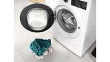 Bosch vaskemaskine med åben luge og lille bunke vasketøj foran