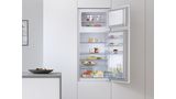 Réfrigérateur-surgélateur encastrable Bosch porte ouverte avec vue sur des provisions et des boissons.