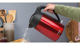 Чайник DesignLine красного цвета и цвета нержавеющей стали. Человек наливает горячую воду в чайник.
