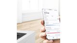 App Home Connect su uno smartphone. Piano cottura intelligente con una padella sullo sfondo.
