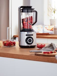 VitaPower Series 8 vacuum blender filled with red fruits placed on kitchen table.