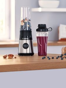 VitaPower Series 2 mini blender filled with blueberries and nuts placed together with filled ToGo bottle on kitchen table.