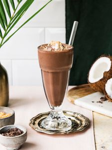 Un shake de ciocolată cu gheață și o nucă de cocos pe fundal.