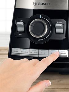 O persoană care dă clic pe butonul de curățare al blenderului Bosch VitaBoost Series 6 pentru a porni programul de curățare.