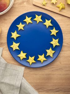 Scheiben einer gelben Sternfrucht sind auf einem blauen Teller angeordnet, um die europäische Flagge darzustellen.