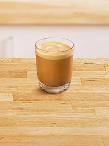 Glass cup filled with cortado coffee.