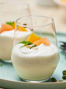 Ein Glas voll mit köstlichem hausgemachtem Joghurt, mit Clementinen dekoriert. 