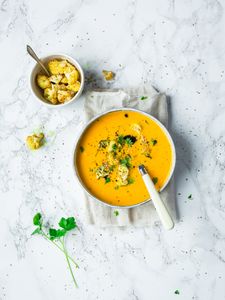 Le soupe de carotte Cookit saupoudrée de sésamé rôti et servie avec du chou-fleur en accompagnement.