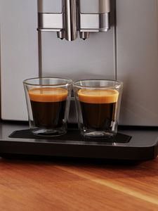 Dwie filiżanki espresso na tacce ociekowej ekspresu VeroCafe Serie 2.