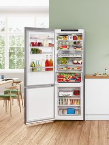 Eine offene und prall gefüllte Kühl- Gefrierkombination steht in einem modernen und hellen Raum.