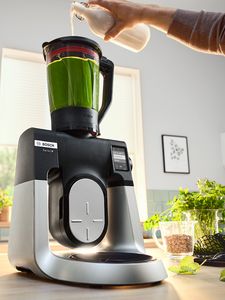 Image shows Series 6 with glass blender accessory and liquid being added to green ingredients.