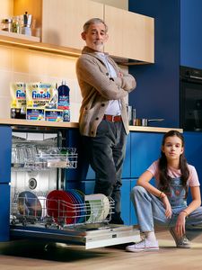 Adult and child in kitchen next to open Dishwasher with Finish bundle on top