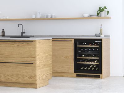 Modernioje ąžuolinėje spintelėje minimalistinėje virtuvėje įmontuota vyno spintelė su LED apšvietimu.