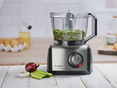 Food processor with shredded food and attachments on kitchen countertop