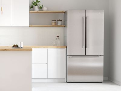Moderne åpent kjøkken med et frittstående kjøleskap med franske dører i hjørnet.