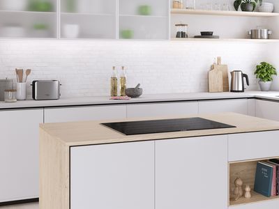 An island with an induction hob in a white and wood kitchen.  