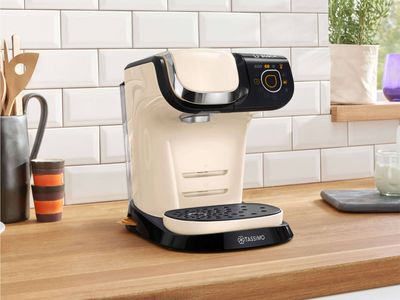 The TASSIMO coffee machine MYWAY 2 standing with a Latte Macchiato on a kitchen worktop.