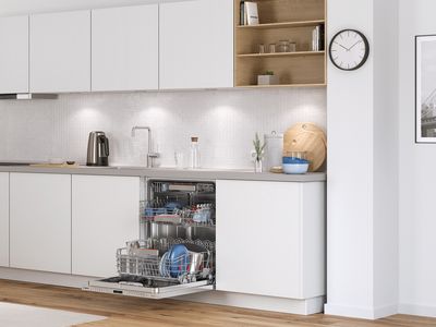 Otvorená vstavaná umývačka riadu Bosch v modernej bielej kuchyni.
