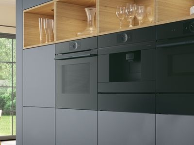 Moderne, dunkelgraue Küche mit Holzregalen und drei schwarzen horizontal eingebauten Hausgeräten.