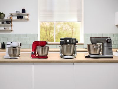 Une gamme des trois modèles de robots de cuisine multifonctions MUM sur un plan de travail de cuisine.