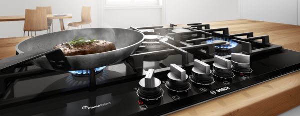 כיריים מתוצרת Bosch עם FlameSelect במטבח לבן מודרני מציגות את היתרונות של בישול בגז.