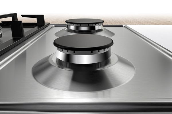 Un gros plan sur une table de cuisson à gaz Bosch en inox met en évidence la surface lisse facile à nettoyer.