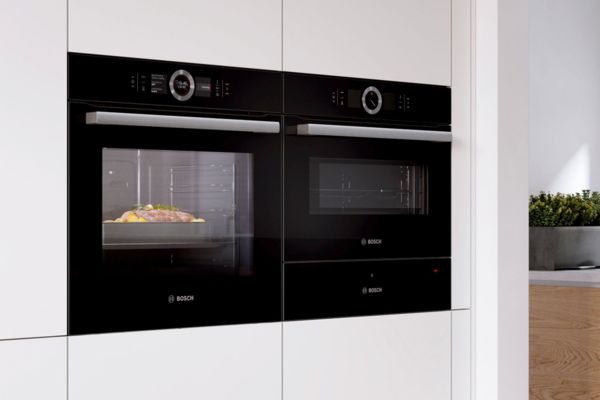 Bosch rerna i ploča za kuvanje u modernoj kuhinji sa kutkom za doručkovanje na levoj strani predstavlja pun asortiman Bosch kućnih aparata i dodatnog pribora.