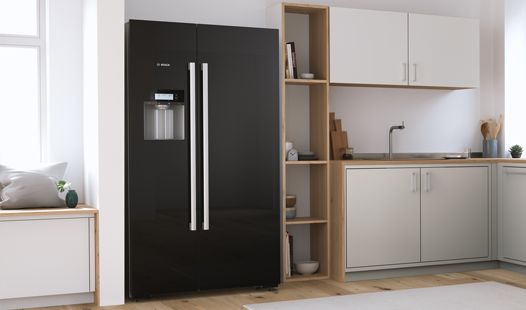 Черный отдельностоящий холодильник Bosch с двумя огромными дверцами на светлой современной кухне.