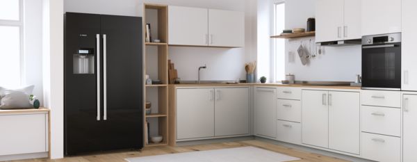Schwarzer, freistehender Kühlschrank von Bosch mit zwei breiten Türen in einer modernen, lichtdurchfluteten Küche.