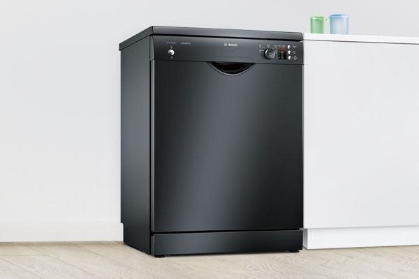 Melna brīvstāvoša Bosch trauku mazgājamā mašīna baltā virtuvē.