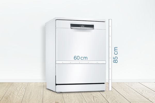 Samostojeća mašina za pranje sudova širine 60 cm na drvenom podu naslonjena na beli zid.