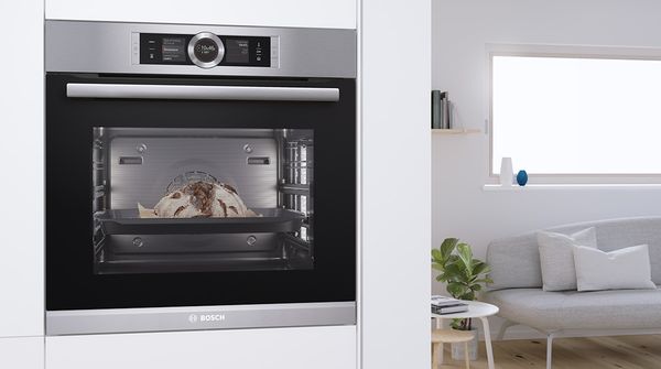 A must-have for baking enthusiasts: a built-in steam oven with a loaf of bread inside, installed at eye level in an open plan kitchen