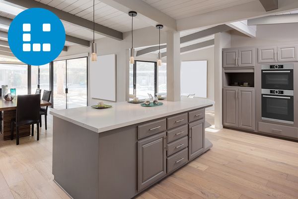 Fényes és modern, nyitott terű konyha, előtérben egy szürke szekrénnyel, egy konyhaszigettel és beépített főzőberendezésekkel