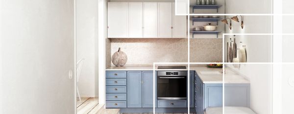 Rustic small L-shaped farmhouse kitchen in matte pastels with built-in oven and brass and earthenware decor.