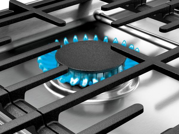 Tuvplāns ar zilu liesmu uz gāzes gatavošanas virsmas degļa
