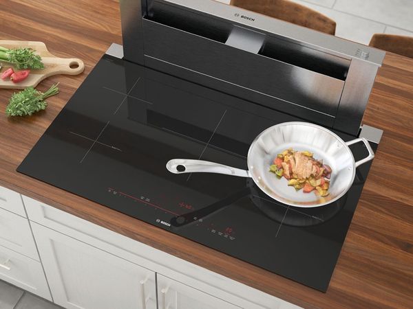 Stainless steel appliance set including a pull-out hood integrated in a compact beige kitchen