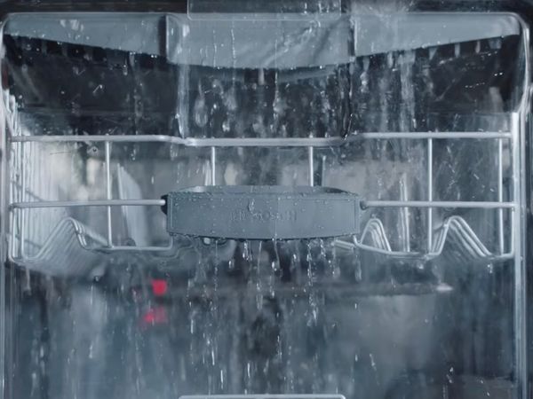 Cascada de agua dentro de un lavavajillas compacto con brazos rociadores moldeados con precisión