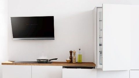 Balta virtuvė su ąžuoliniu stalviršiu, aukštųjų technologijų garų rinktuvu ir įmontuojamaisiais virtuvės prietaisais. Alyvuogių aliejus ir prieskoniai ant stalviršio