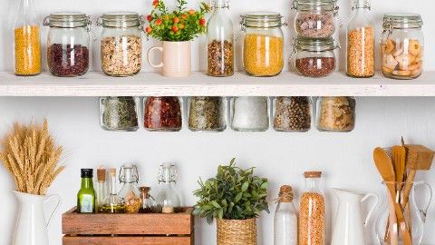 Simple open shelf with glass jars on both sides holding a colorful mix of spices, cereals and pasta