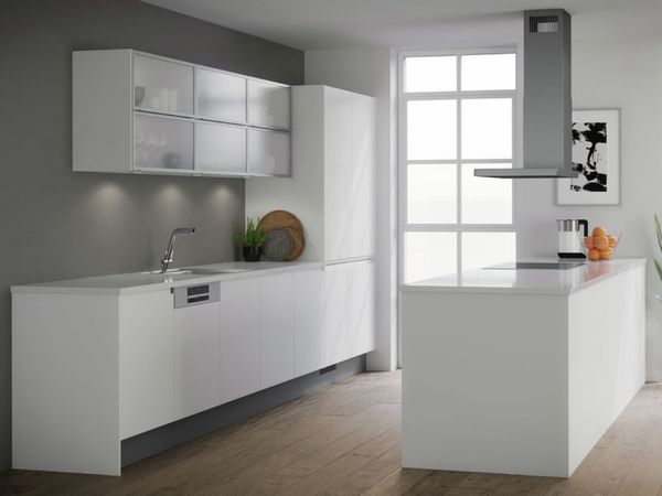 Cucina con isola e paraschizzi in marmo bianco e mobili grigi con superficie riflettente. La cucina dispone di forno classico, forno compatto, piano cottura e cappa.