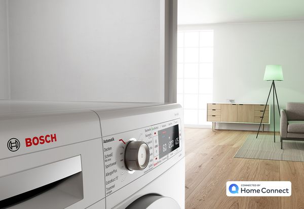 Bosch Waschmaschine mit eingeschalteter Stehlampe im Hintergrund symbolisiert die Verknüpfung aller Smart Home Geräte mit Busch Jaeger.