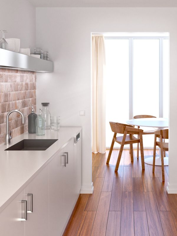 Bucătărie alb-negru cu panou de protecție la stropire contrastant, cu textură de cărămidă roz. Bucătărie lungă și îngustă cu un cuptor și o hotă, iar la capătul ei se află masa de sufragerie, în altă cameră.