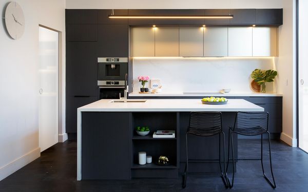 Jet black frameless cabinets in a matte finish paired with white countertops and tasteful indirect lighting