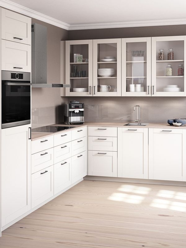 Cream-coloured L-shaped kitchen set against an earthy grey wall. Small seating nook