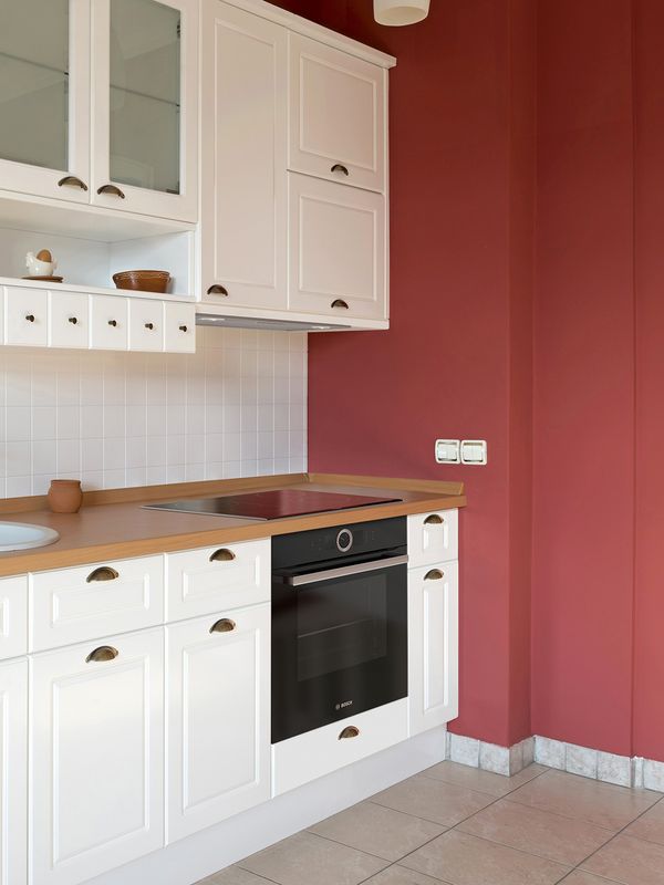 Omarice z belim okvirom s kuhinjskimi pripomočki v opečnati barvi na klasičnem lesenem pultu