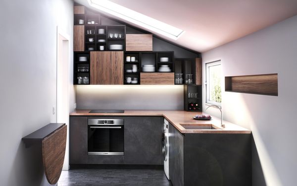 Bucătărie minusculă într-o cameră mică, cu acoperiș înclinat și luminator. Bucătăria prezintă un spațiu de depozitare modular, folosind suprafața înclinată și ușile dulapului de culoare castanie și blaturile.