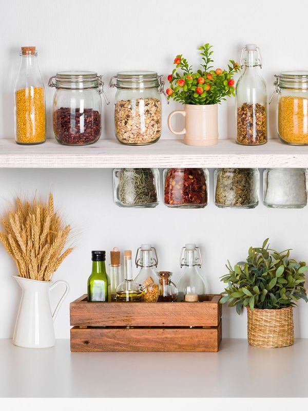 Colección de especias y cereales en diferentes frascos unidos a ambos lados de un estante abierto sobre una encimera