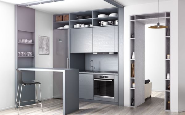 Bucătărie mică, cu dulapuri gri fără cadru, cu aspect de oțel șlefuit. Nișe și rafturi atractive în pereți și împrejurul cadrului deschis al ușii